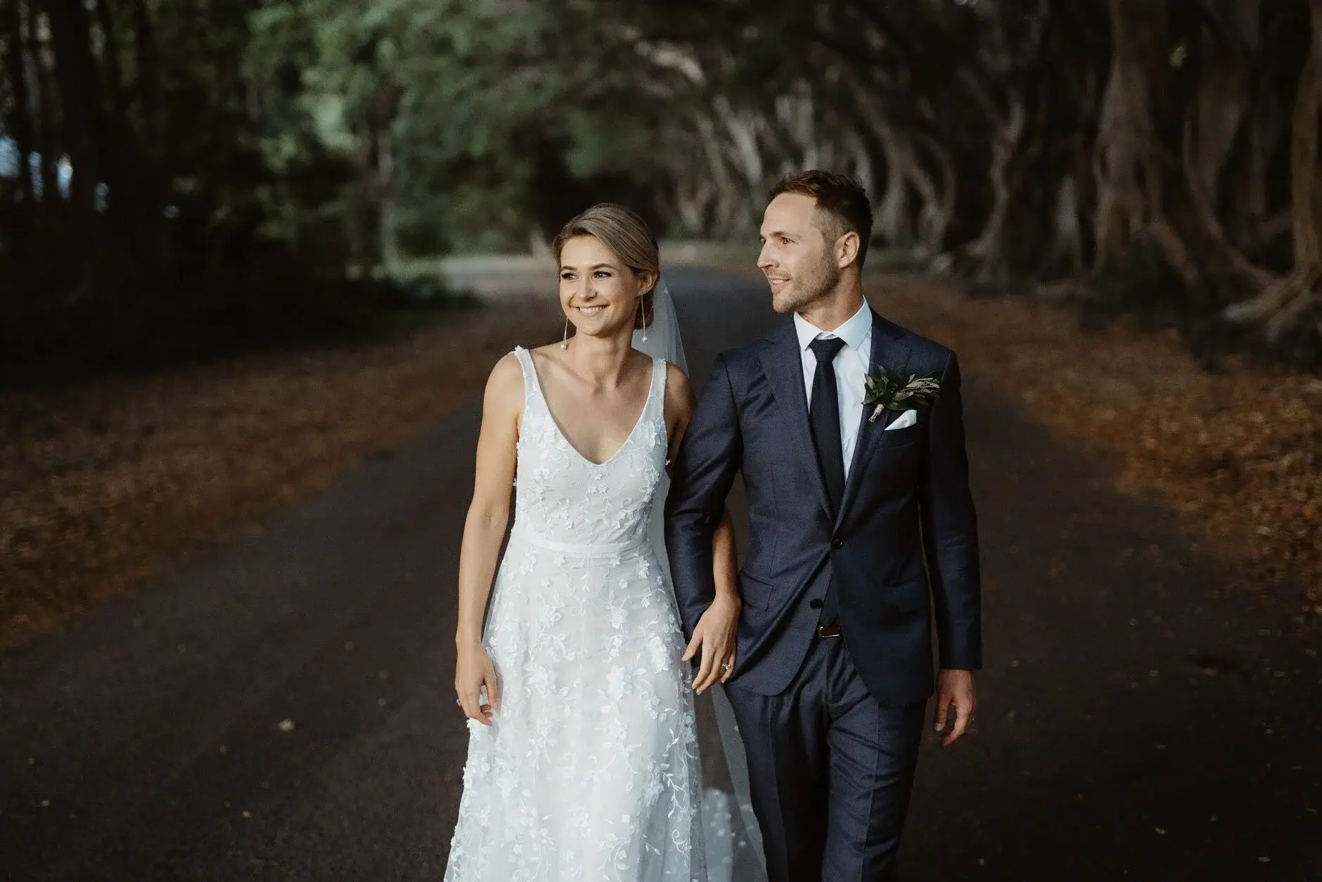 Em and Nev walking the tree-lined road together, Byron Bay