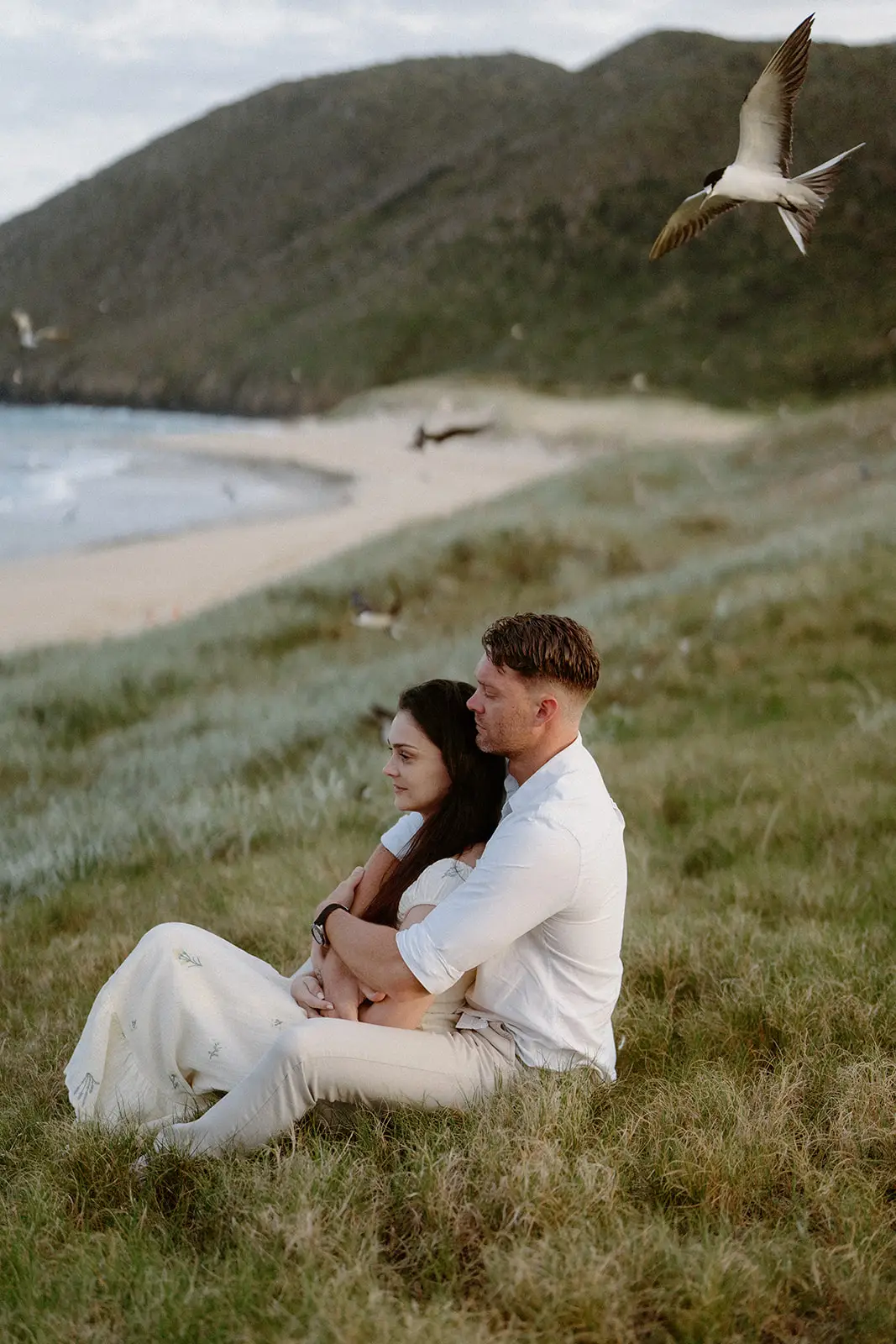 Mel and Brent sitting on the grass above the beach, Lord Howe Island