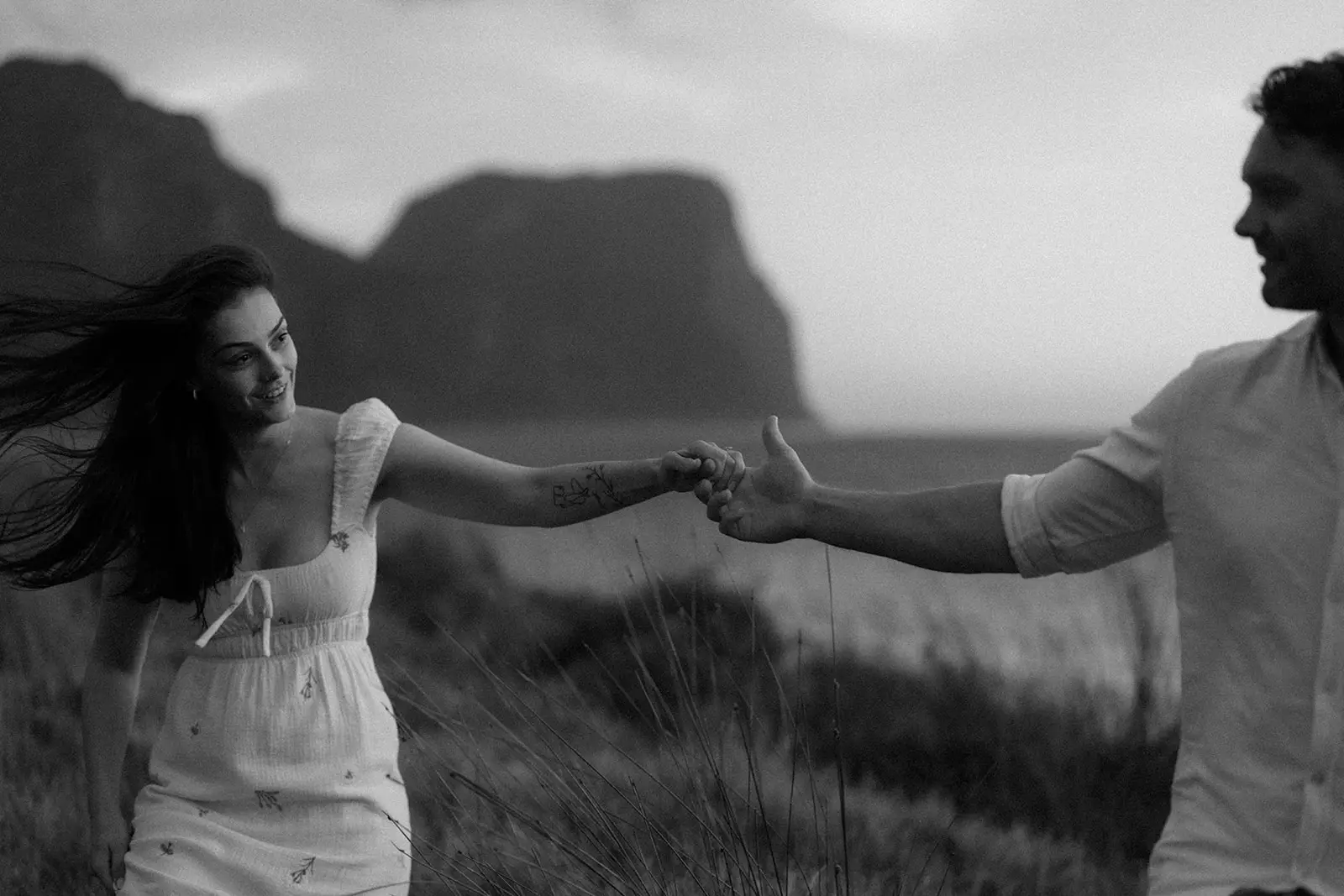 Brent pulling Mel along by the hand, mountains behind, Lord Howe Island